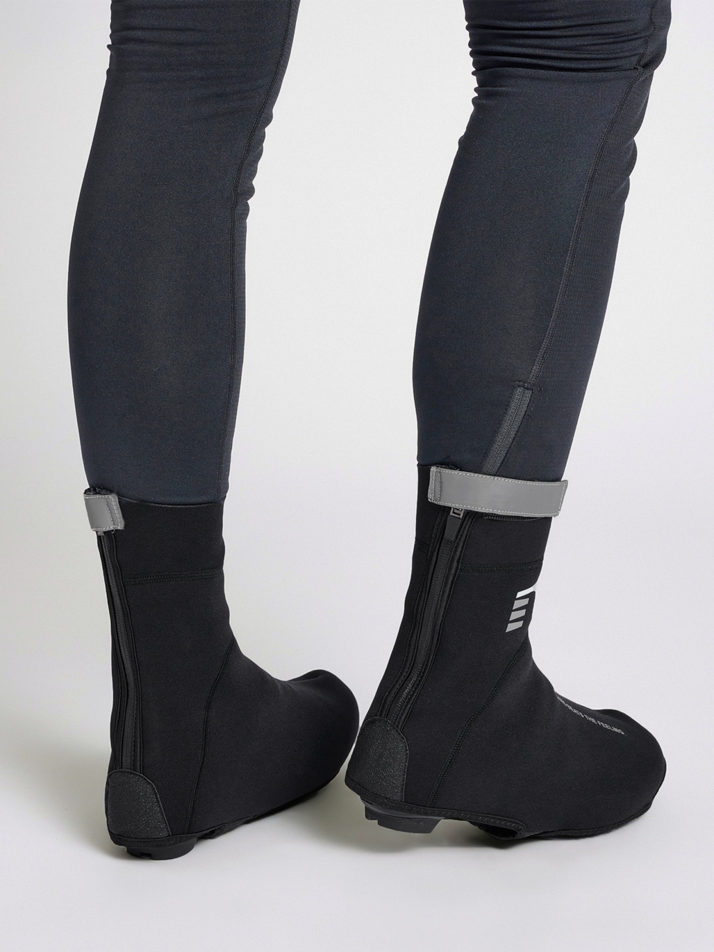 Black thermal cycling shoe covers, rear zip view on model