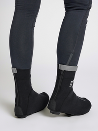 Black thermal cycling shoe covers, rear zip view on model